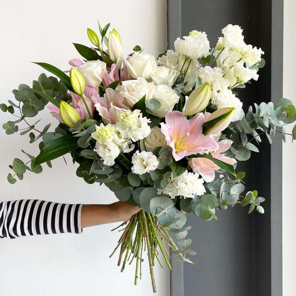A lovely bouquet with white roses, double flowering white lisianthus, dainty and fragrant pink lilies and eucalyptus cineria.